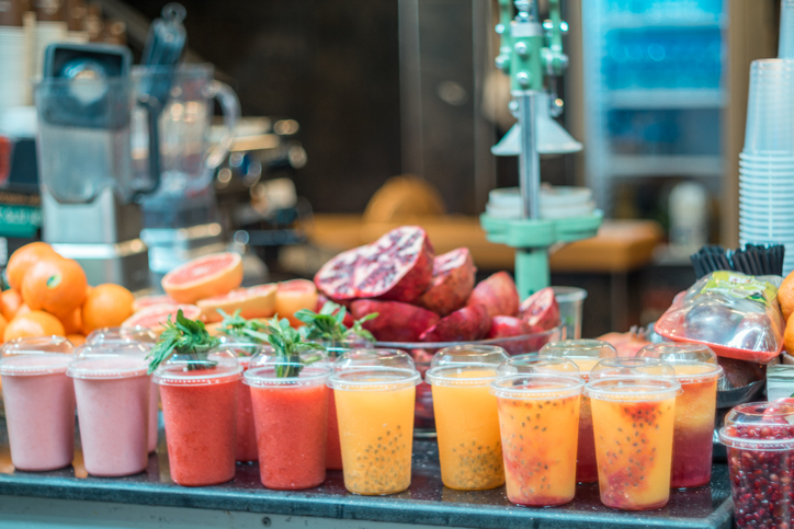 Fresh blended fruit smoothies of various colors and tastes shops for produce in food market